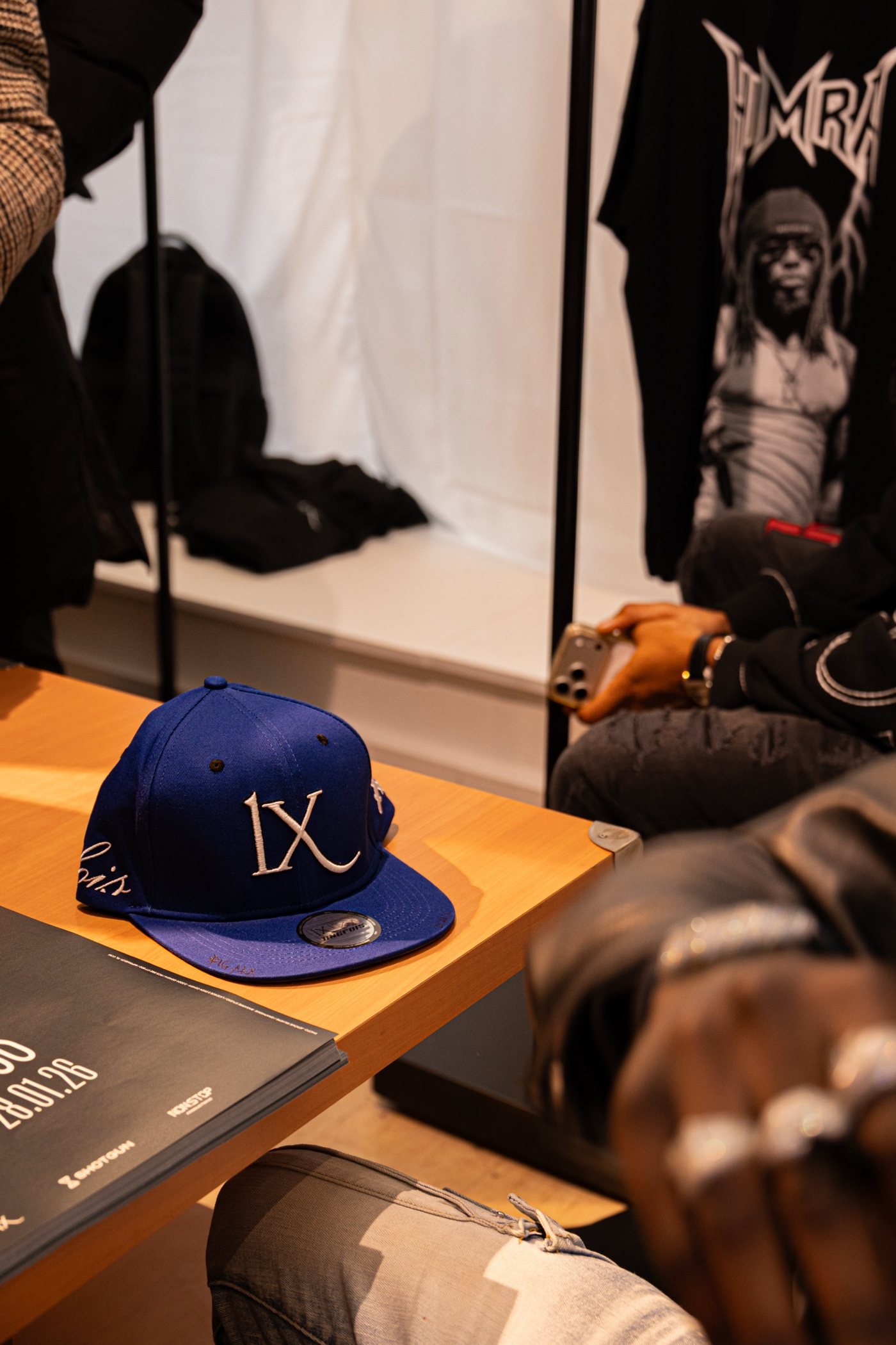 Pop-up store : casquette bleue brodée posée sur la table, t-shirt en fond