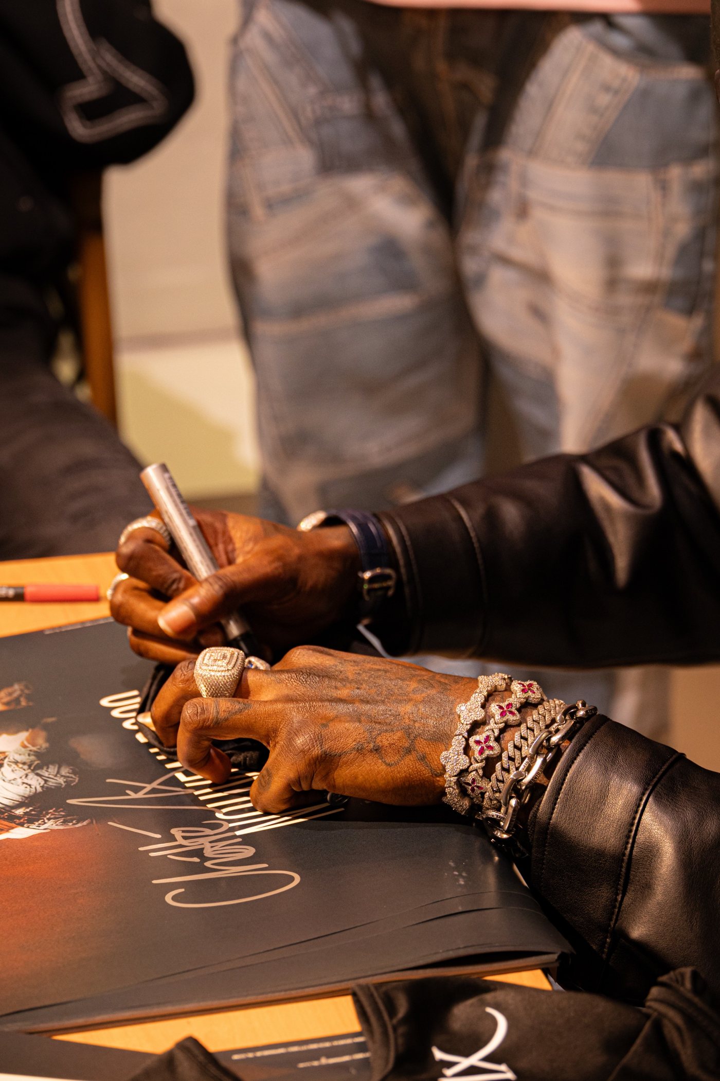 Dédicace : signature au feutre sur une affiche, bracelets et bagues