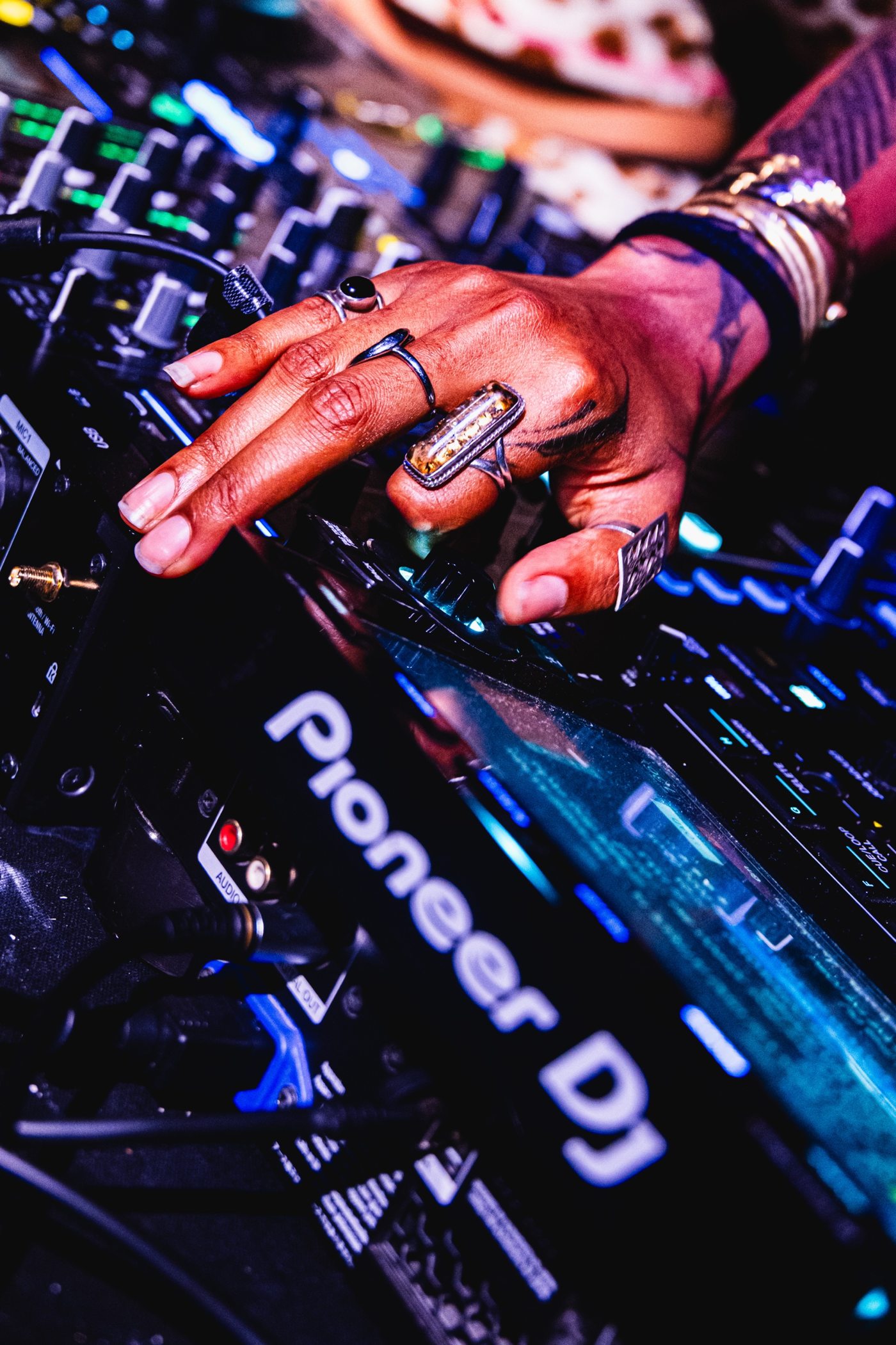 Gros plan d'une main aux bagues sur une table de mixage Pioneer DJ