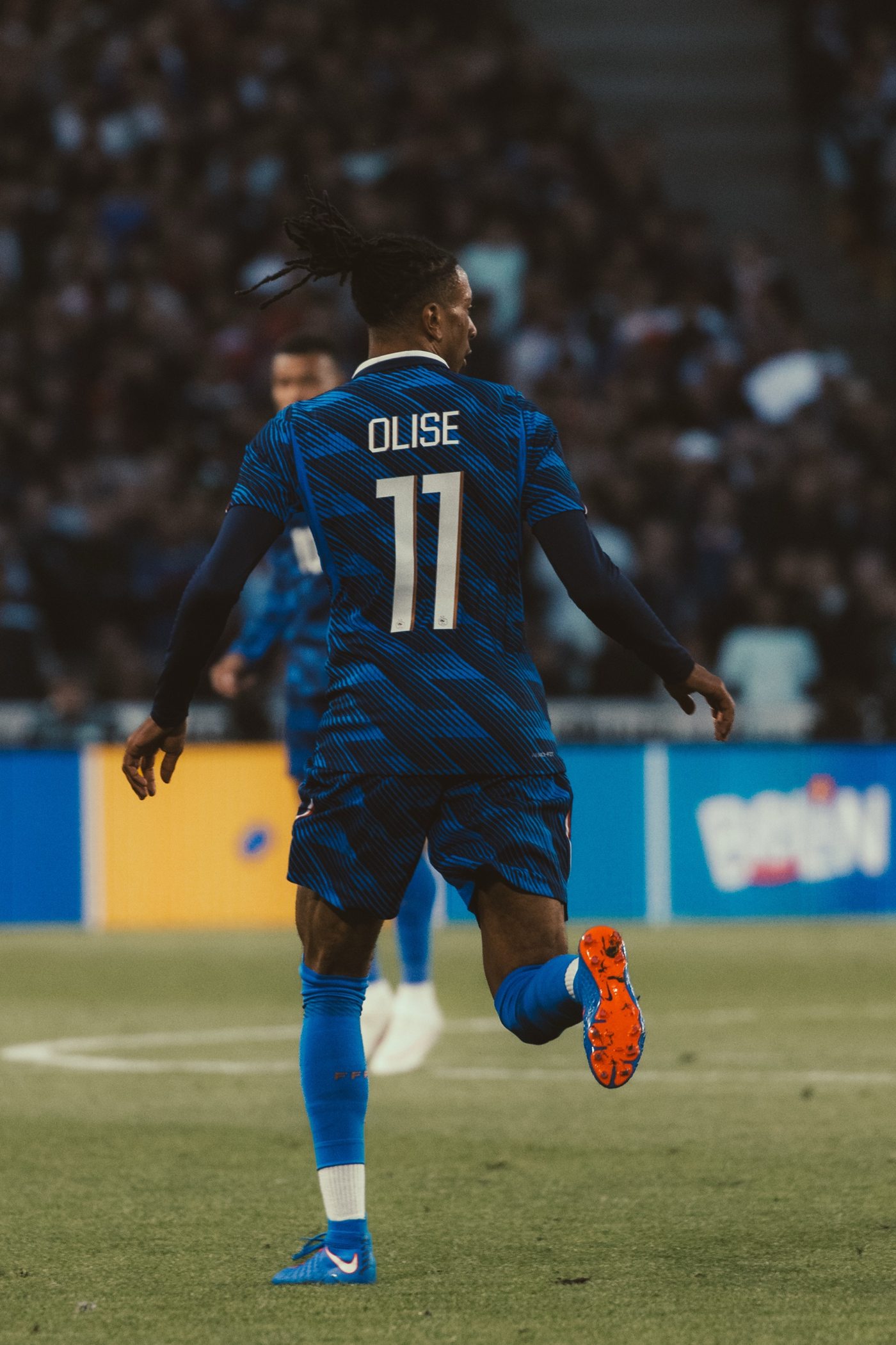 Football : Olise de dos en pleine course, crampons orange vif aux pieds