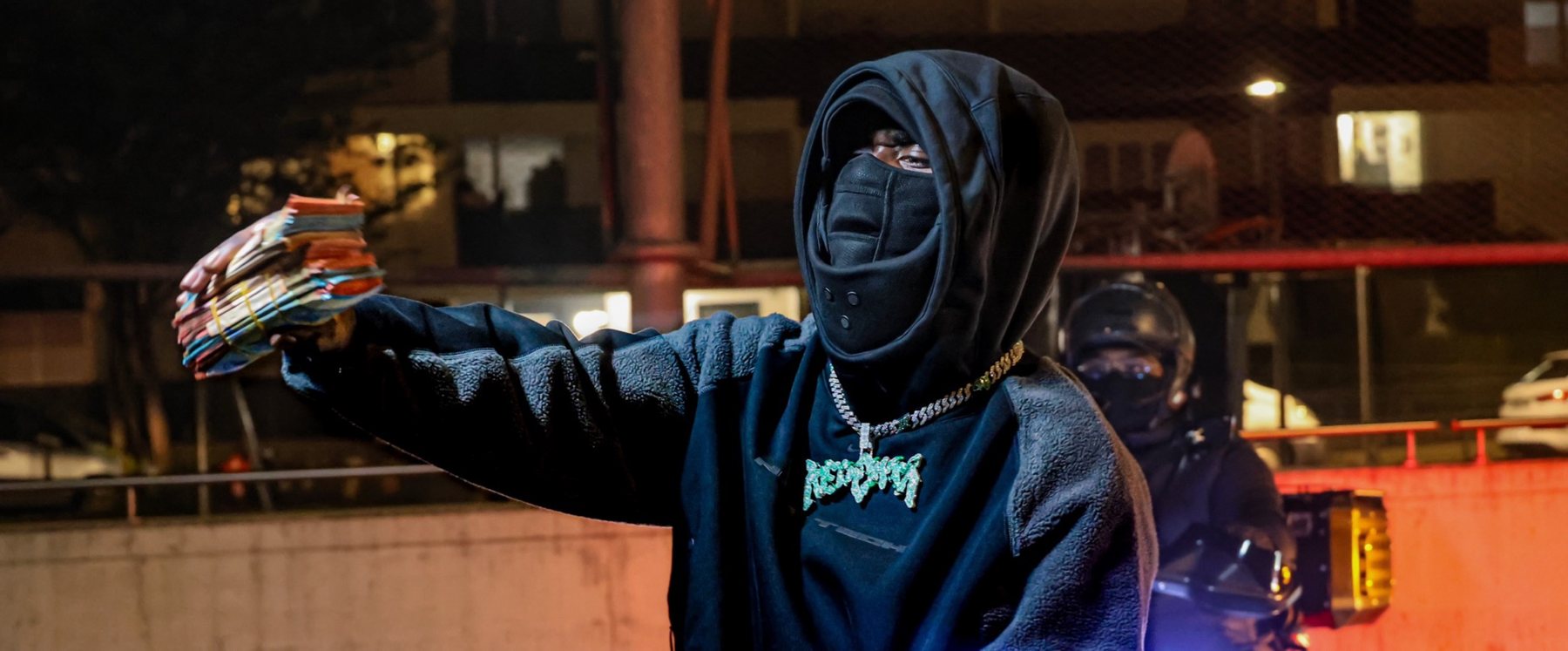 Homme encapuchonné de nuit, bras tendu