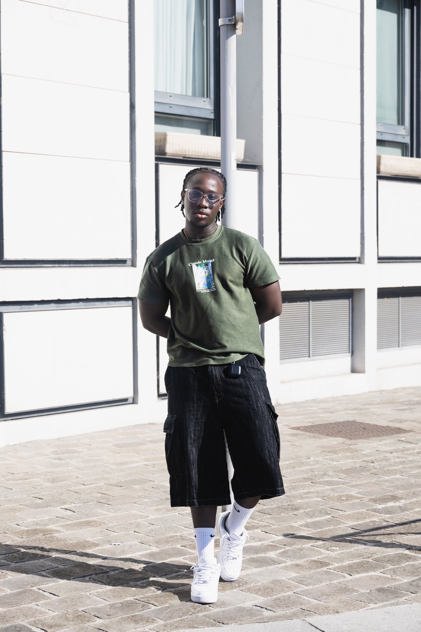 Look streetwear : t-shirt kaki, bermuda en jean noir et baskets blanches