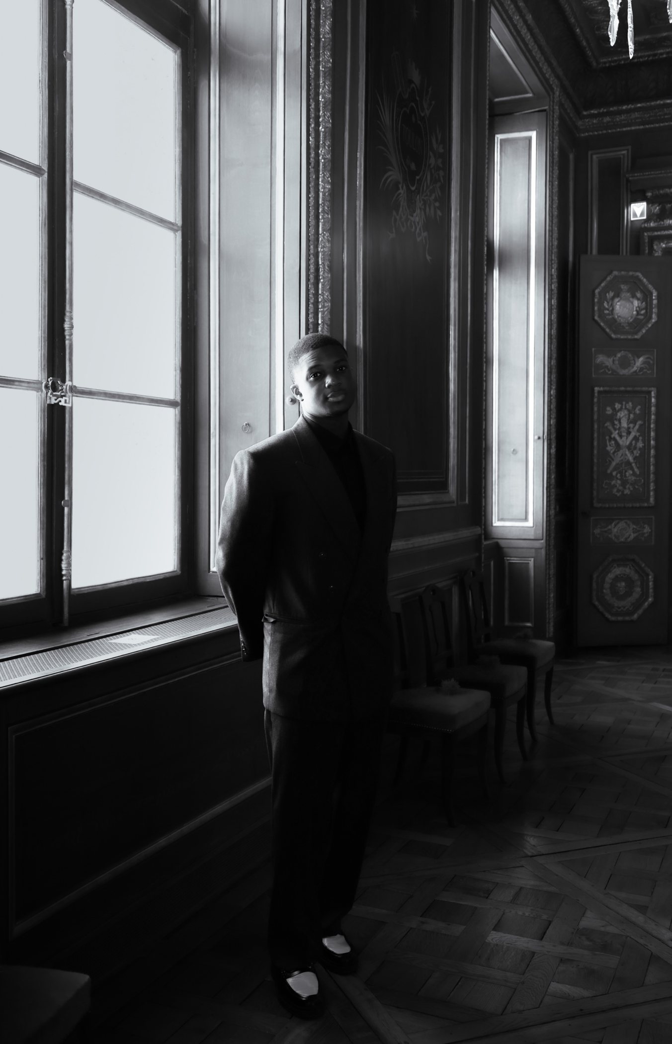 Costume sombre dans un salon à boiseries, noir et blanc