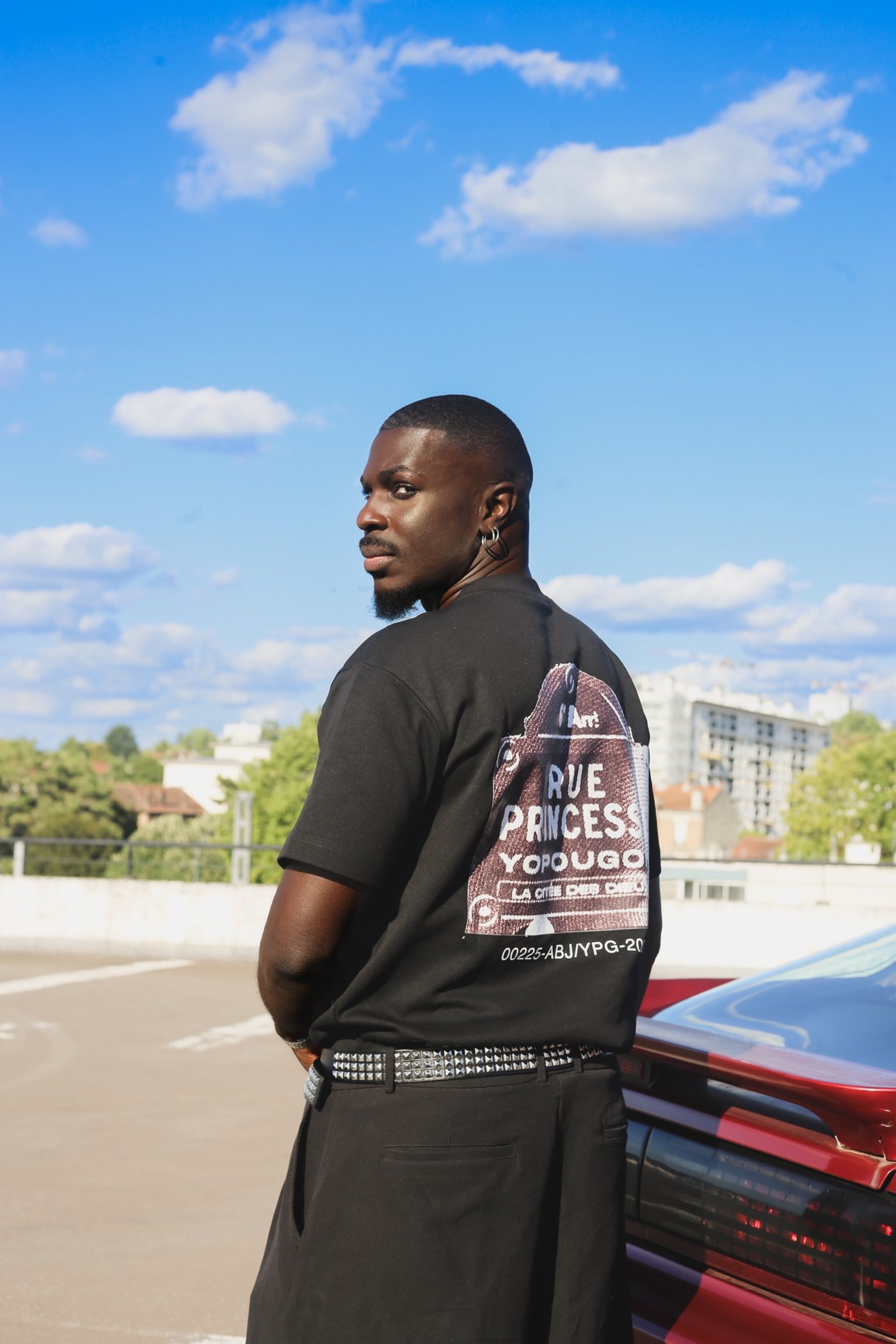 T-shirt noir imprimé dans le dos, ciel bleu et voiture rouge