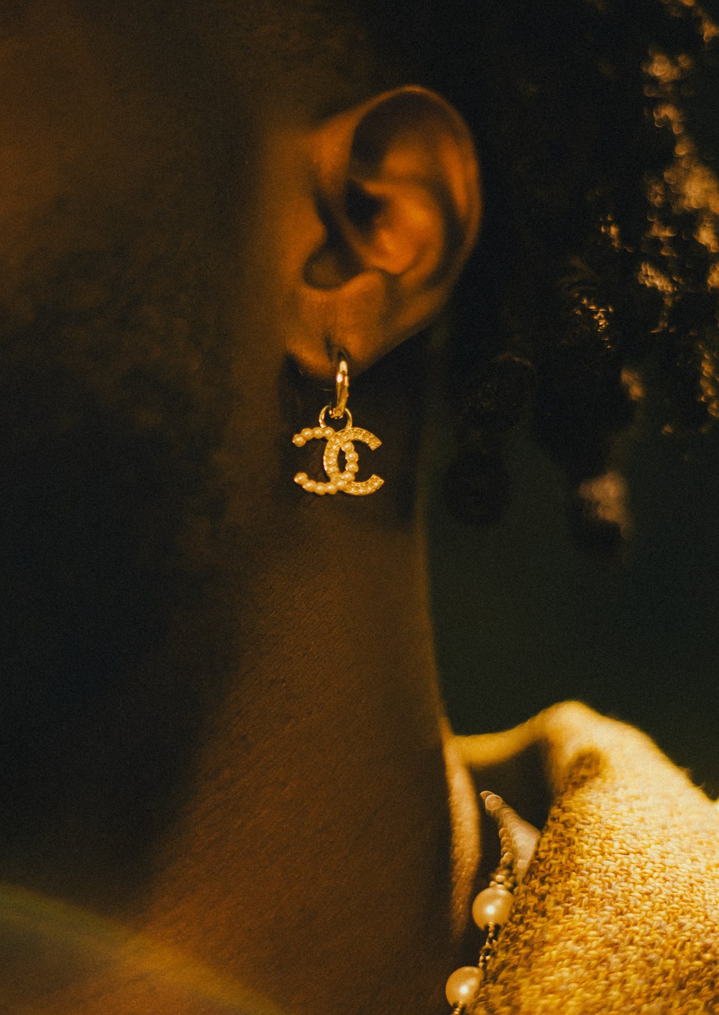 Gros plan sur une boucle d'oreille CC perlée, lumière dorée