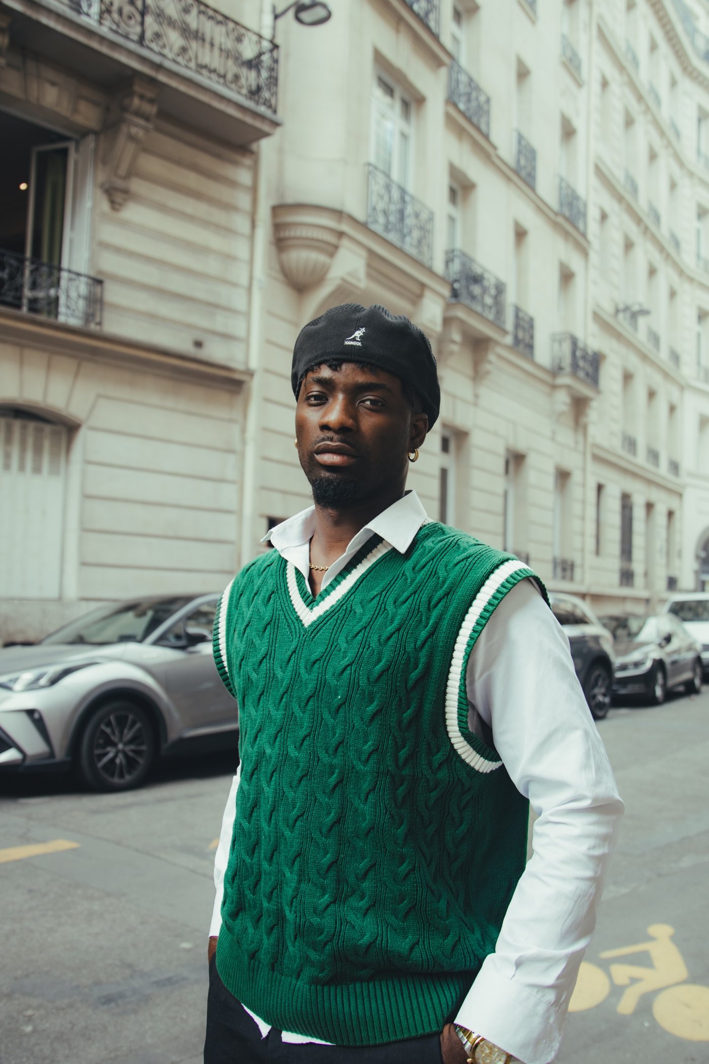 Portrait dans une rue de Paris, pull vert sans manches et béret Kangol