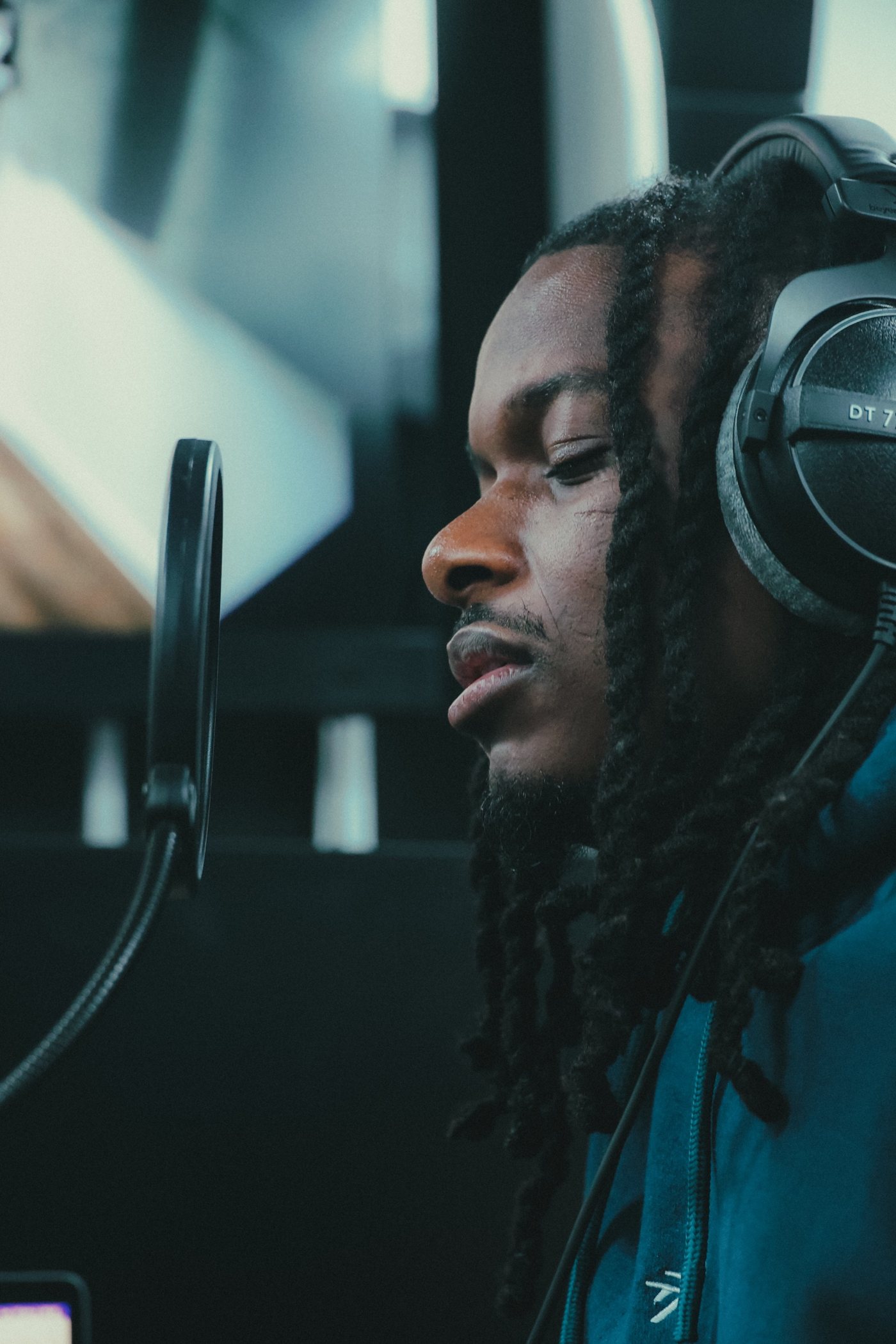 Studio : gros plan de profil sur l'artiste devant le micro, casque audio