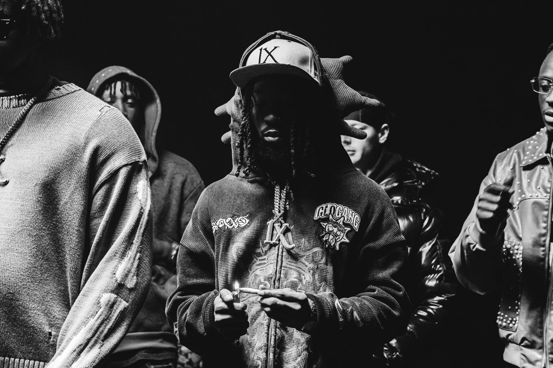 Un homme en casquette IX allume un joint, hoodie brodé