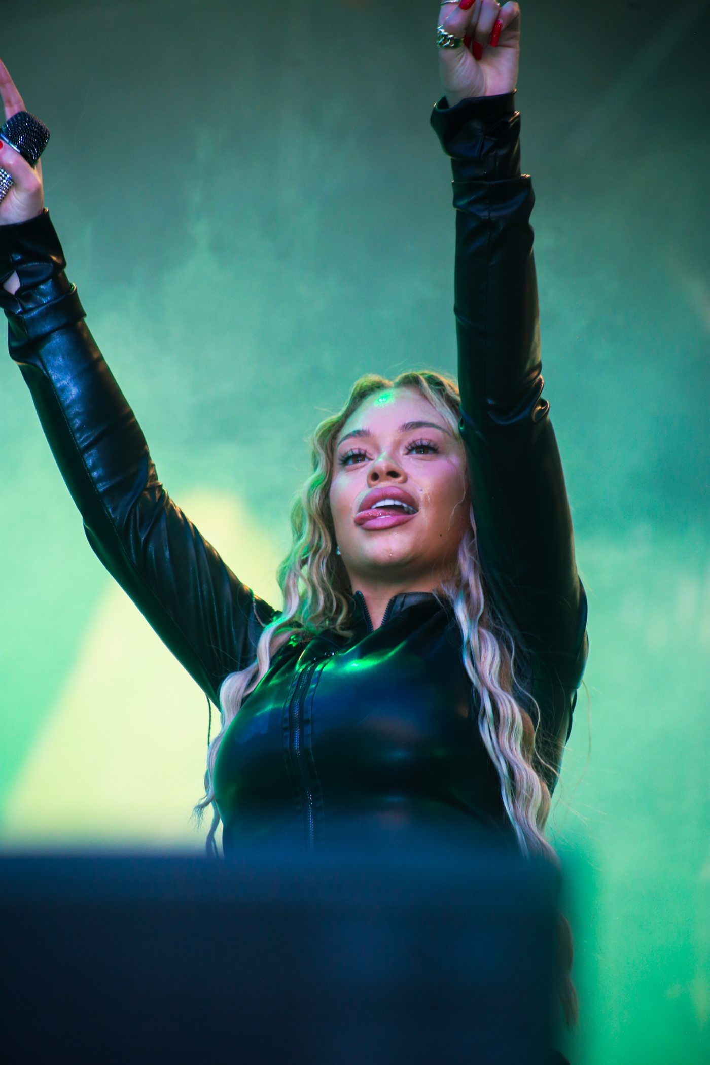 Chanteuse les bras levés sur scène, fumée verte